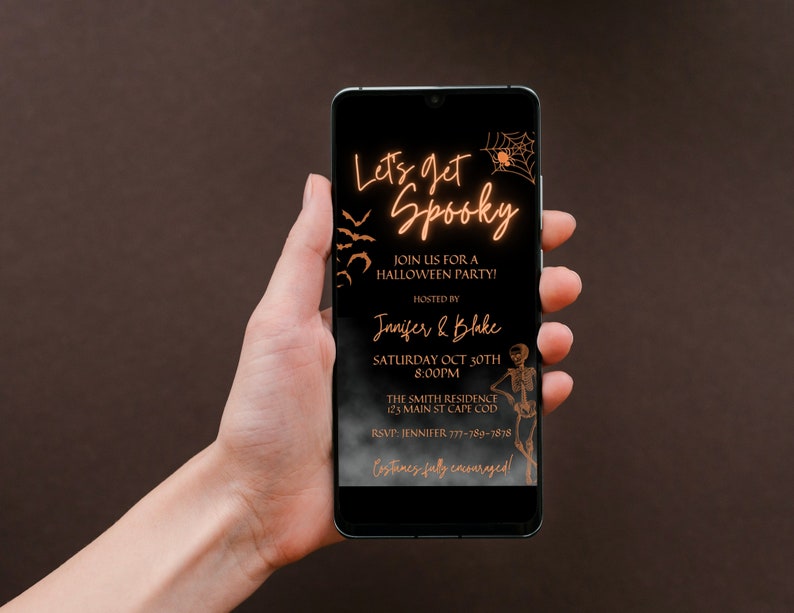 K&ouml;nnte beinhalten: Ein Smartphone, auf dem eine Halloween-Partyeinladung mit schwarzem Hintergrund und orangefarbenem Text angezeigt wird. Die Einladung lautet "Let's get Spooky" und enth&auml;lt Details zur Party, einschlie&szlig;lich Datum, Uhrzeit, Ort und RSVP-Informationen. Die Einladung zeigt auch ein Spinnennetz und ein Skelett.