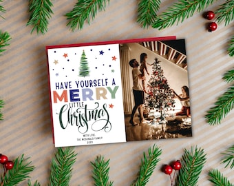 Puede incluir: Una tarjeta de Navidad con una familia decorando un árbol de Navidad. La tarjeta tiene el texto "Have Yourself a Merry Little Christmas" con la palabra "Merry" en letras de colores. El texto "With Love, The McDonald Family 2023" está en la parte inferior de la tarjeta.