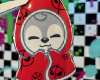 May include: A red hooded character with a white face and black eyes. The hood and the character's body are covered in a pattern of black eyes and a diagonal line.