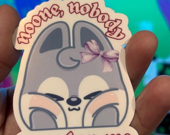 May include: A sticker featuring a cartoon animal with a light gray body, pink cheeks, and a purple bow. The sticker has the text "noone, nobody can stop me" in a pink font.