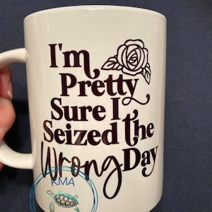 May include: White ceramic coffee mug with a black design that reads "I'm Pretty Sure I Seized the Wrong Day". The design also includes a black rose.