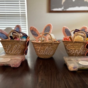 Peut inclure: Trois petits paniers tissés avec des oreilles de lapin et des noms personnalisés : Lilly, Hallie et Sophia. Chaque panier est rempli de divers petits objets, dont des jouets, des lunettes de soleil et des accessoires pour cheveux.