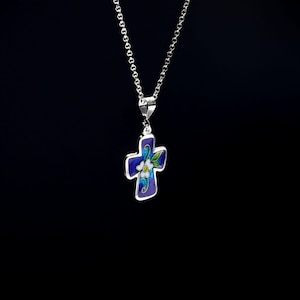 May include: A silver chain necklace with a blue enamel cross pendant featuring a white flower design.