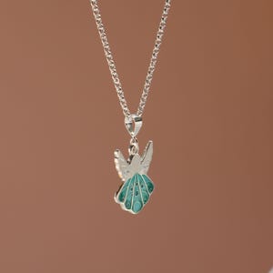 Op de afbeelding: Een zilveren ketting met een hanger in de vorm van een turquoise blauwe engel met zilveren vleugels.
