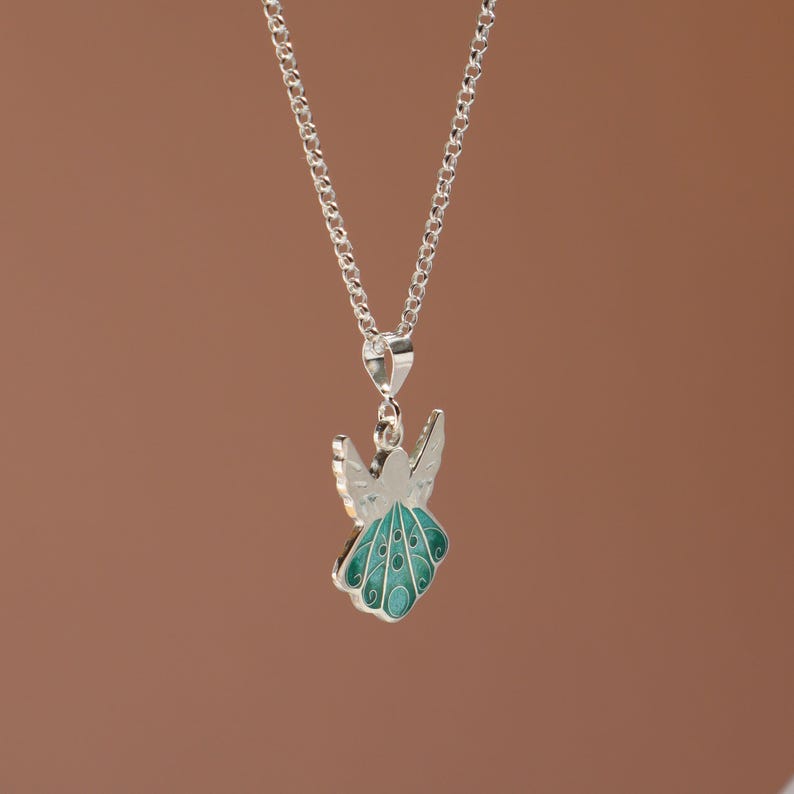 Op de afbeelding: Een zilveren ketting met een hanger in de vorm van een turquoise blauwe engel met zilveren vleugels.