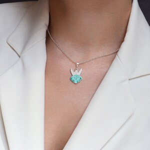Op de afbeelding: Een zilveren ketting met een groene emaille engel hanger. De engel heeft vleugels en een halo.