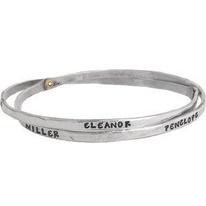 May include: Silver double bangle bracelet with the names "Eleanor Miller" and "Penelope" engraved on it.