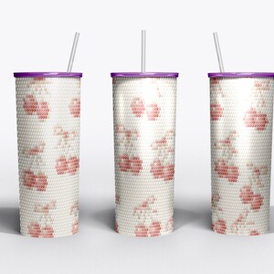 Pode incluir: Três canecas isoladas com fundo branco. Cada uma tem uma tampa roxa, um canudo branco e um padrão de flores cor-de-rosa. As canecas são projetadas para manter as bebidas frias ou quentes.