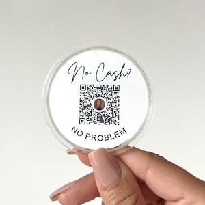 Könnte beinhalten: Ein runder weißer Aufkleber mit dem Text "No Cash?" und einem schwarz-weißen QR-Code. Der Text "NO PROBLEM" ist unter dem QR-Code gedruckt.