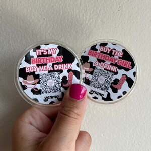 Puede incluir: Dos posavasos redondos de plástico transparente con diseños de estampado de vaca en blanco y negro. Un posavasos dice "It's My Birthday Buy Me A Drink" con un corazón rosa y un código QR. El otro posavasos dice "Buy The Birthday Girl A Drink" con un corazón rosa y un código QR. Ambos posavasos tienen la palabra "Venmo" impresa.