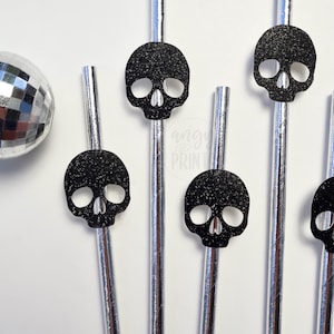 Puede incluir: Seis pajitas de papel plateadas con recortes de calaveras de purpurina negra. Las pajitas son perfectas para una fiesta de Halloween.