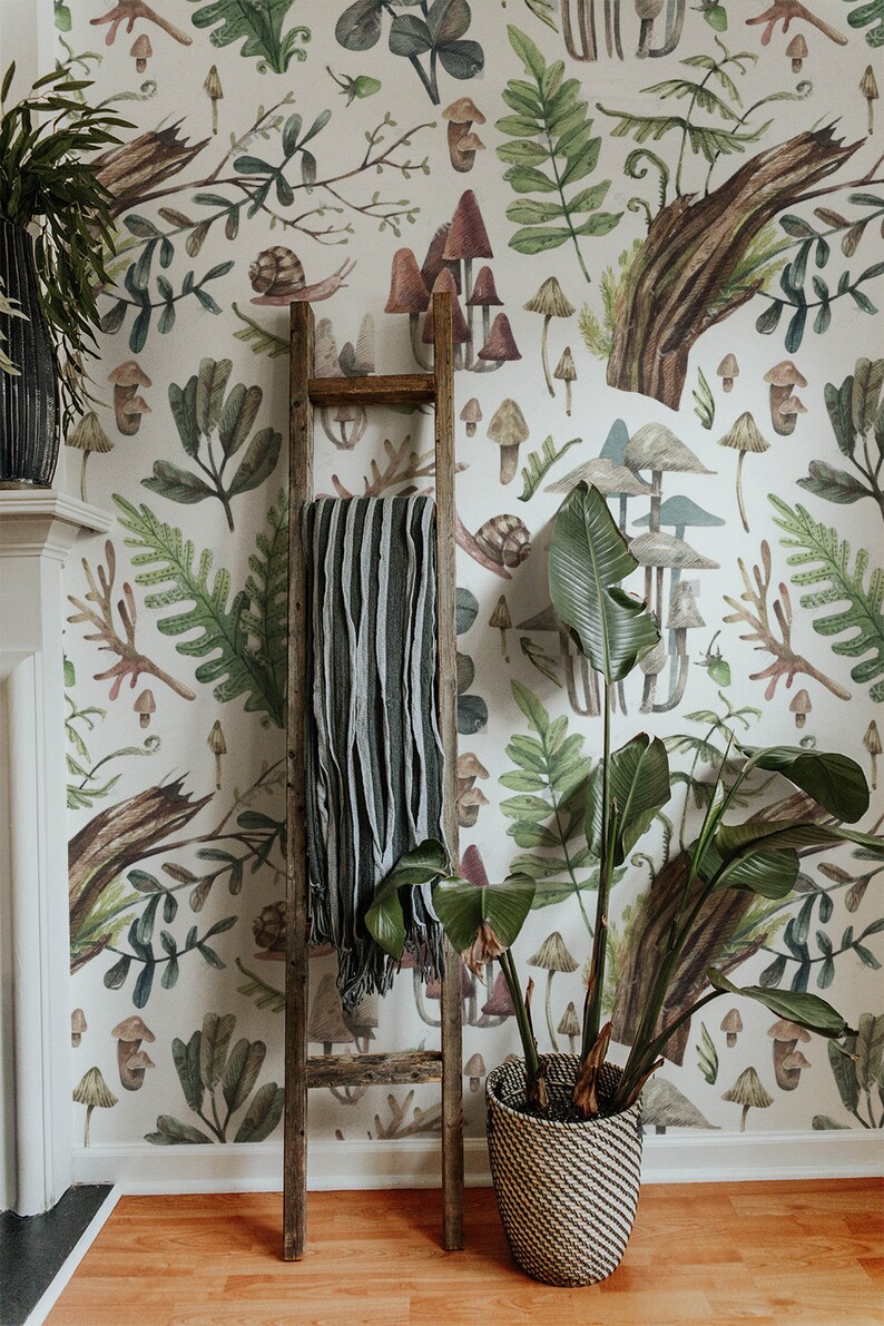 May include: A room with forest-themed wallpaper featuring mushrooms, ferns, and snails. A wooden ladder leans against the wall, with a striped blanket. A large potted plant with broad leaves sits in a woven basket.