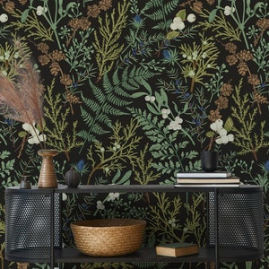 May include: Dark wallpaper featuring a botanical pattern with green, brown, and white plant illustrations on a black background. A black metal console table holds a woven basket, books, and decorative vases. The overall theme is nature and home decor.
