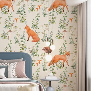 May include: A bedroom with a whimsical forest-themed wallpaper featuring foxes, mushrooms, and greenery. The room includes a blue bed, decorative pillows, a teddy bear, and a small side table. A modern light fixture hangs from the ceiling.