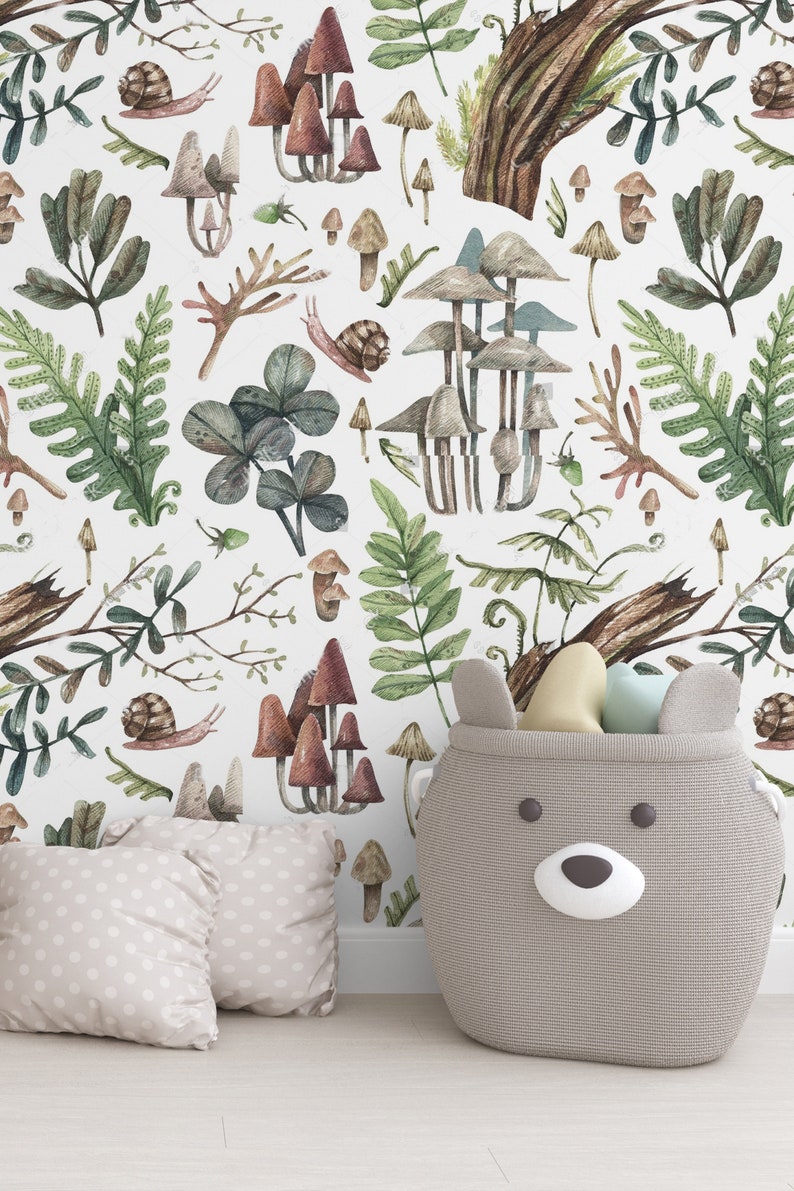 May include: A nursery scene with woodland-themed wallpaper featuring mushrooms, ferns, and snails. A grey bear-shaped storage basket holds toys. Two beige polka-dot pillows are on the floor. The scene is light and airy.