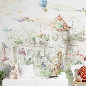 May include: A watercolor illustration of a whimsical castle with a rainbow, a hot air balloon, and a fairy flying in the sky. The castle is surrounded by lush greenery and flowers. A stuffed giraffe and rabbit are sitting in front of the illustration.