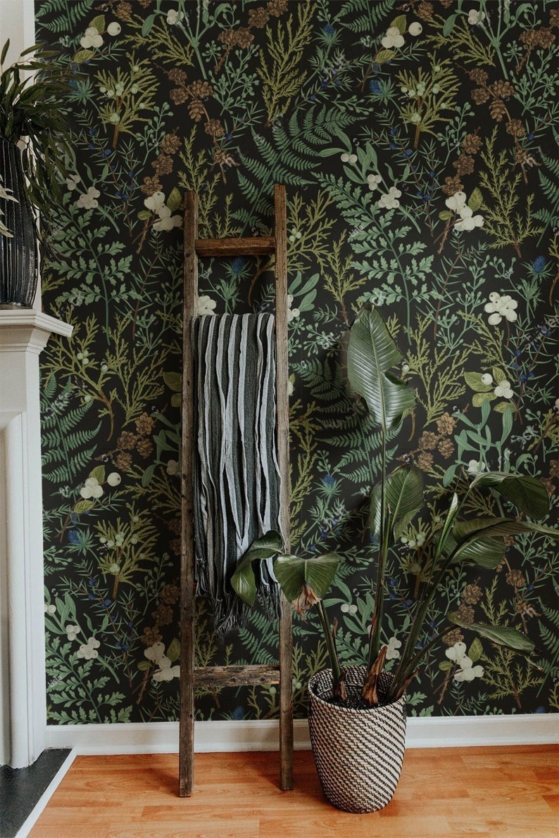 May include: A room with a dark floral wallpaper featuring green, white, and brown botanical elements. A wooden ladder leans against the wall, with a striped blanket draped over it. A potted plant with large green leaves sits in a woven basket.