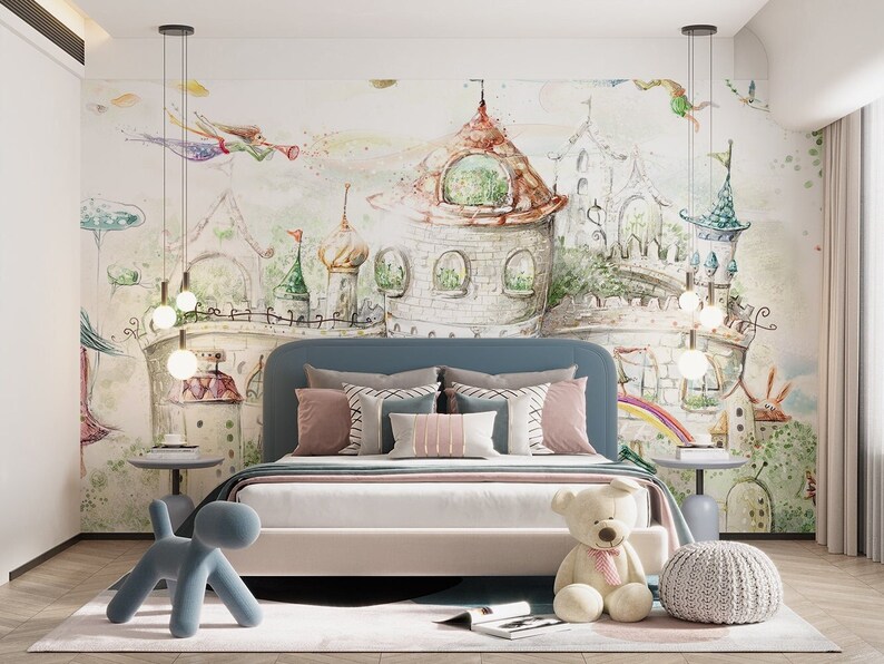 May include: A blue upholstered bed with a white duvet and a colorful cartoon castle mural on the wall behind it. The bed has a teddy bear and a blue dog toy on the floor in front of it.