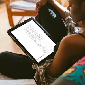 May include: A person sitting on a couch and looking at a tablet. The tablet screen shows a black and white architectural drawing of a building floor plan. The text on the tablet reads "THE DRAWINGS FOR THE FLOOR PLAN".