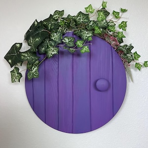 May include: A purple round wooden door with a small knob, decorated with green ivy vines.