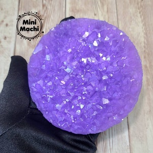 May include: A round, purple resin coaster with a sparkly, crystal-like texture. The coaster is approximately 3 inches in diameter.