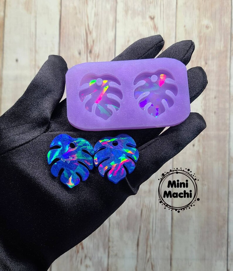 May include: Purple silicone mold with two leaf-shaped cavities. Two iridescent blue resin leaves are shown next to the mold. The text "Mini Machi." is printed on a black circle.