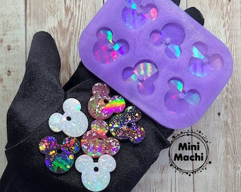 May include: Purple silicone mold with six Mickey Mouse head shapes.  There are six finished resin Mickey Mouse head shapes with iridescent glitter in various colors.