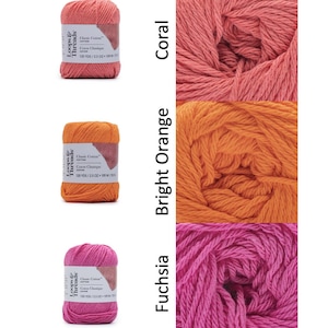 Op de afbeelding: Drie strengen Loops & Threads Classic Cotton garen in koraal, fel oranje en fuchsia. Elke streng is gelabeld met de merknaam en productdetails. Het garen wordt weergegeven naast close-ups van het garen in elke kleur, waarbij de textuur en tint worden getoond.