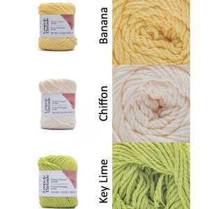 Op de afbeelding: Drie bollen Loops & Threads Classic Cotton garen in de kleuren Banana, Chiffon en Key Lime. Elke bol is gelabeld met de merknaam, het garentype en de afmetingen: 120 YDS / 70.87 g / 100 g.