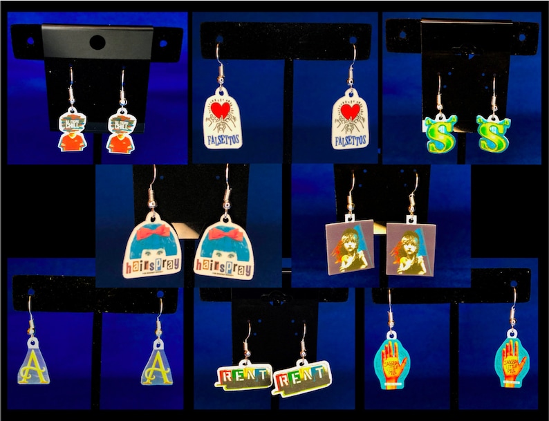Peut inclure: Une collection de boucles d'oreilles pendantes vari&eacute;es. Les motifs incluent des personnages de dessins anim&eacute;s, le mot "Falsettos" avec un c&oelig;ur, le mot "Hairspray", la lettre "S", un portrait de femme, la lettre "A", le mot "Rent" et une main avec du texte.