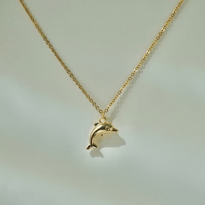 May include: A gold chain necklace with a dolphin pendant.