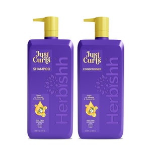 May include: Two purple bottles of Just Curls shampoo and conditioner. The bottles are labeled with the product name, "Just Curls", and the product type, "Shampoo" and "Conditioner". The bottles are also labeled with "Vegan with Avocado & Coconut Oil" and "Free From Formaldehyde, Parabens, Ammonia, Sulfates, Silicones, Cruelty". The bottles are 16.9 fl oz / 500 ml.