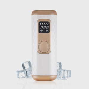 May include: A white and gold handheld device with a digital display showing numbers and symbols. The device has a button and a textured pattern. Ice cubes are in the foreground.