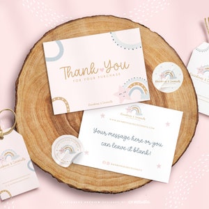 Op de afbeelding: Een briefpapier set met twee rechthoekige kaarten, twee ronde stickers en twee labels met touw. De items zijn wit met een pastelkleurig regenboog-, ster- en wolkenontwerp. De tekst bevat Thank You For Your Purchase en Rainbows & Coconuts.