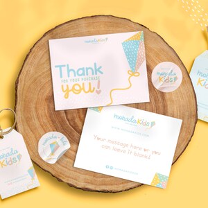 May include: A set of thank you cards and gift tags with a kite design. The cards are pink and white with a blue and yellow kite. The tags are blue and white with a yellow kite. The text on the cards says "Thank you!" and "For your purchase". The text on the tags says "mohada Kids".