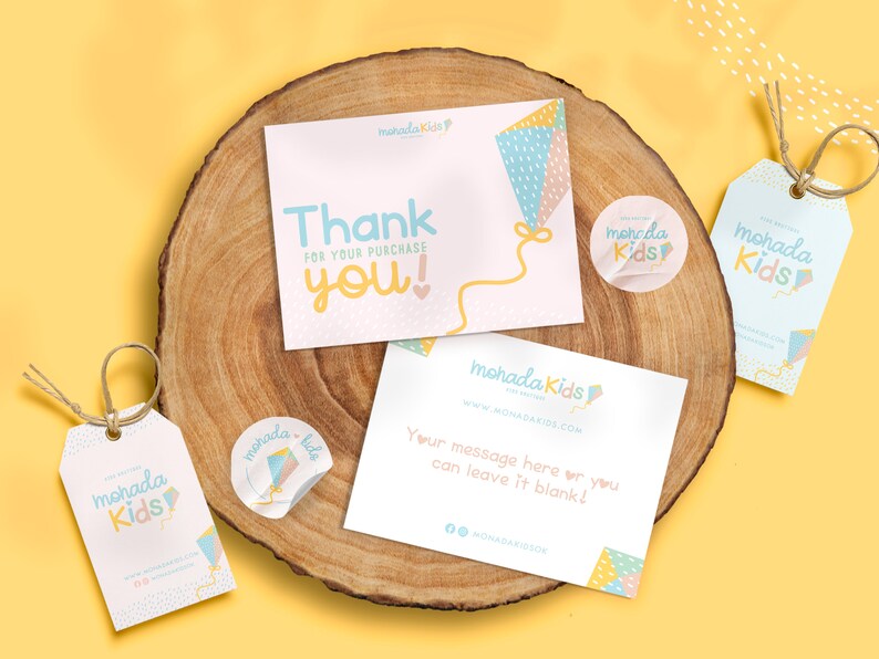 May include: A set of thank you cards and gift tags with a kite design. The cards are pink and white with a blue and yellow kite. The tags are blue and white with a yellow kite. The text on the cards says "Thank you!" and "For your purchase". The text on the tags says "mohada Kids".