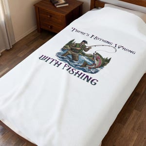 Puede incluir: Funda de cama blanca con un diseño de pesca. La ilustración muestra a un pescador pescando una trucha, con el texto "THERE'S NOTHING WRONG WITH FISHING" en azul oscuro. El diseño incluye árboles y agua.