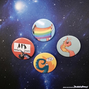 Könnte beinhalten: Vier runde Ansteckbuttons mit Krakenarmen. Einer zeigt eine Regenbogenflagge, einer hat einen roten Hintergrund mit dem Text "AfD verbot jetzt!", einer ist gelb mit einem Arm, der eine Tasse hält und "this is fine" zeigt, und einer zeigt eine Blume.
