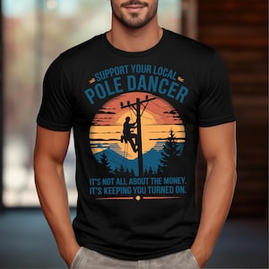 Könnte beinhalten: Ein schwarzes T-Shirt mit einer Grafik im Vintage-Stil, die einen Linienmann zeigt, der einen Strommast hinaufklettert. Der Text lautet "Unterstütze deinen lokalen Pole-Dancer. Es geht nicht nur ums Geld. Es hält dich am Laufen."