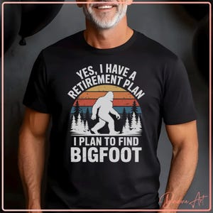 Puede incluir: Camiseta negra con un gráfico de Bigfoot y el texto "Yes, I have a retirement plan. I plan to find Bigfoot." El diseño presenta un atardecer retro y una escena de bosque.