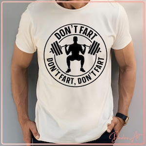 May include: White t-shirt with a black circle graphic featuring a silhouette of a person lifting weights and the text "Don't fart, don't fart, don't fart".