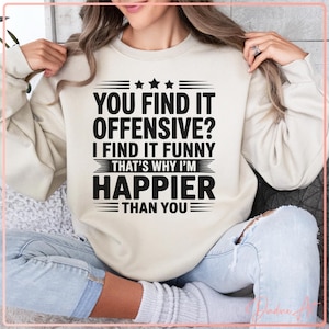 Op de afbeelding: Een crèmekleurige sweatshirt met de zwarte tekst: "YOU FIND IT OFFENSIVE? I FIND IT FUNNY THAT'S WHY I'M HAPPIER THAN YOU". De sweatshirt heeft een ronde hals en lange mouwen.