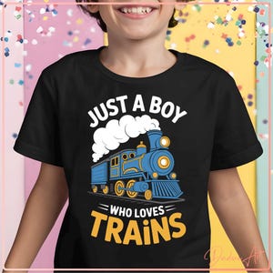 May include: Black t-shirt with a blue and yellow train graphic. The text reads "JUST A BOY WHO LOVES TRAINS" in white and yellow. The train design features a steam engine with smoke billowing from the smokestack. A fun, colorful design for train enthusiasts.
