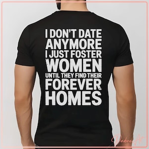 Può includere: T-shirt nero con testo bianco: "I DON'T DATE ANYMORE I JUST FOSTER WOMEN UNTIL THEY FIND THEIR FOREVER HOMES." La maglietta è a girocollo. Il testo è in grassetto, senza grazie.