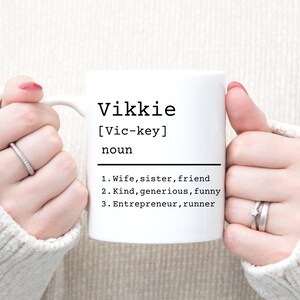 May include: White ceramic mug with black text that reads "Vikkie [Vic-key] noun 1. Wife, sister, friend 2. Kind, generous, funny 3. Entrepreneur, runner"