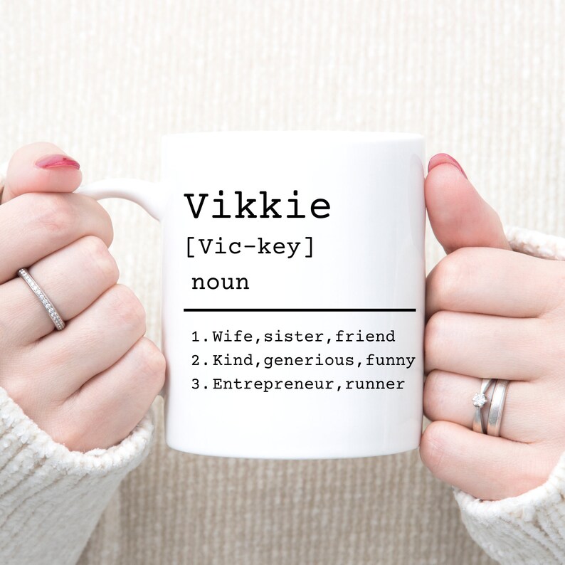 May include: White ceramic mug with black text that reads "Vikkie [Vic-key] noun 1. Wife, sister, friend 2. Kind, generous, funny 3. Entrepreneur, runner"