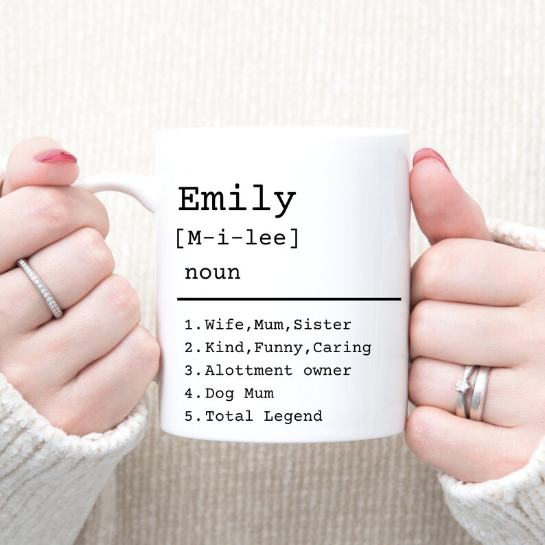 May include: White ceramic mug with a black design that says "Emily [M-i-lee] noun 1. Wife, Mum, Sister 2. Kind, Funny, Caring 3. Allotment owner 4. Dog Mum 5. Total Legend"