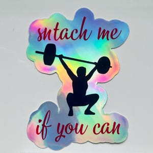May include: Holographic sticker with the words "snatch me if you can" in red script. The sticker features a black silhouette of a person lifting a barbell overhead in a squat position. The sticker has a rainbow iridescent effect.
