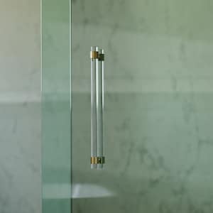 May include: A clear glass shower door with a brass and glass handle. The door is framed in a silver metal frame.