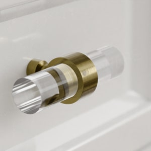 Puede incluir: Un pomo de armario de acrílico transparente con un anillo de metal dorado. El pomo está diseñado para usarse en armarios, cajones y muebles.